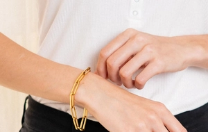 Gros plan d'un bracelet gourmette en acier inoxydable doré porté au poignet d'une femme