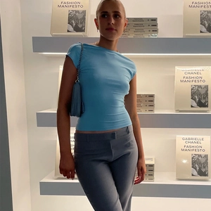 Nauwsluitende lichtblauwe crop top met open rug met bijpassende tas en een grijze broek