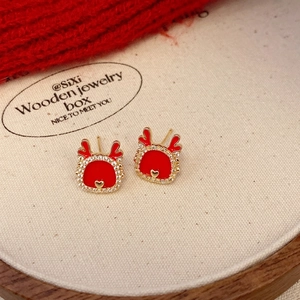 Detailed close-up of red reindeer stud earrings with gold antlers and pavé white zircons