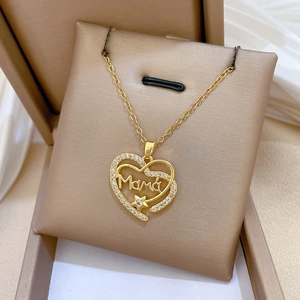 Gros plan d'un pendentif cœur doré avec lettrage Mama et zircon dans un écrin