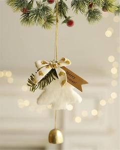 Detail of plush white Christmas tree ornament with golden bell and Merry Christmas tag