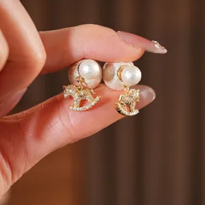 Elegant rocking horse earrings with pearls and crystals in a gold finish for women
