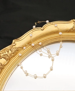 Detailed macro view of multi-layer white pearl necklace with gold chains on vintage mirror