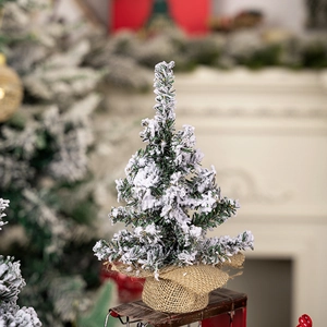 Mini tabletop snowy Christmas tree with flocked branches and a rustic burlap base