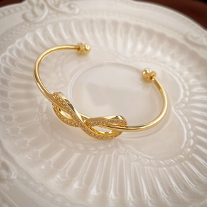 Macro view of infinity bow cuff bracelet with sparkling pavé zircons on ceramic plate
