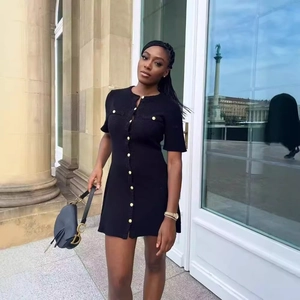 Elegant black knit short sleeve mini dress with gold button details on outdoor model