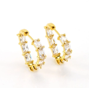 Detailed close-up of golden C-shaped hoop earrings with baguette-cut zircon inlays