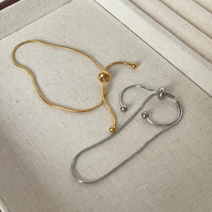 Detail of adjustable gold and silver snake bone bracelets with bead slide clasp closure