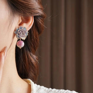Boucles d'oreilles roses rétro avec pétales violets et perles texturées sur modèle