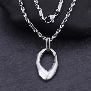 Detailed close-up of a silver irregular teardrop pendant on a textured dark rock base