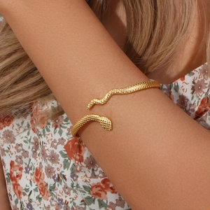 Detail of 18K gold snake bangle featuring intricate scale texture on model wrist