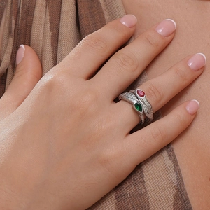 Detailed close-up of a silver snake ring with red and green drop-shaped gemstones