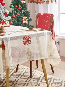 Detail showing red bell and bow embroidery on beige Christmas lace tablecloth