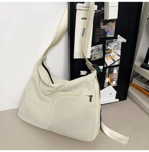 Detail view of durable nylon crossbody bag showing wide strap and metallic zippers