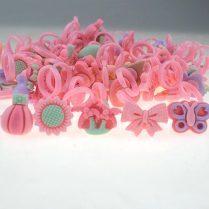 Detailed view of pink plastic toy rings in assorted butterfly and floral shapes for girls