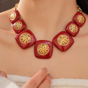 Dettaglio di una collana vintage in smalto rosso con ciondoli quadrati filigranati.