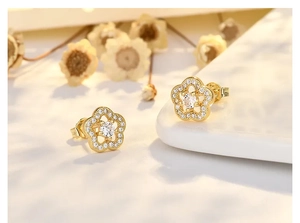 Macro detail of plum blossom stud earrings with micro-inlaid zircons and gold finish