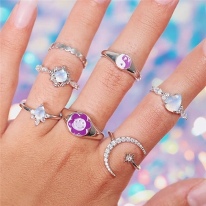 Macro shot of silver rings set with purple enamel flower and zircon moon motifs