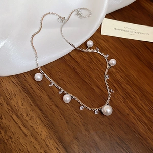 Close-up of elegant pearl and crystal fringe necklace on white silk and dark wood background