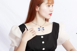 Elegant dragonfly pendant necklace with blue crystals worn by a model on plain background