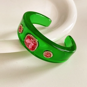 Detail of green vintage resin bangle with pink rhinestones and gold-tone metal accents