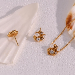 Detailed view of gold pearl necklace and earrings set with crystal on a seashell stand