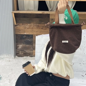 Detailed close-up of brown wool drawstring bag with white polka dots and carry handle