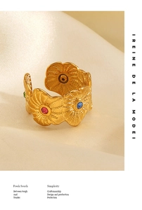 Detailed macro of golden floral ring with colorful gems on elegant white satin fabric