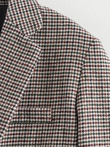 Detail of classic green houndstooth blazer showing notch lapel and tweed fabric texture