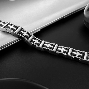 Close-up of punk style stainless steel cross bracelet on a sleek dark surface