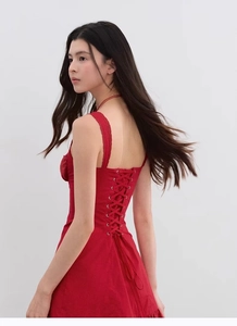 Dettaglio di un abito rosso in pizzo con un elegante design stringato sulla schiena