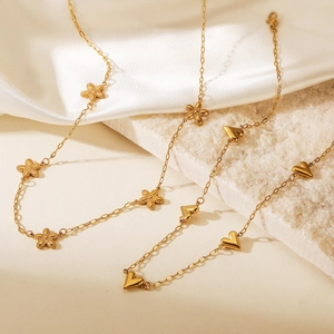 Elegant gold necklaces with heart and flower pendants on white stone and satin fabric