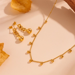 French retro gold beaded necklace and earring set on a minimalist warm background