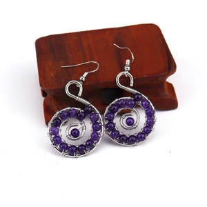 Macro shot of handmade purple crystal beads with silver wire spiral wrap on a hook earring