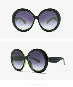 Detail view of oversized round sunglasses with black and green two-tone frame design