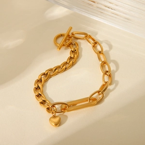 Close-up of golden Cuban chain bracelet with OT toggle clasp and small heart pendant