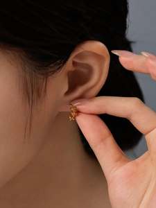 Detailed close-up of 14K gold plated leaf-shaped stud earring worn by a model