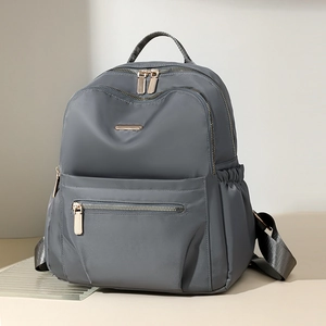 Detail shot of a grey nylon backpack featuring premium gold metal zippers and side pockets