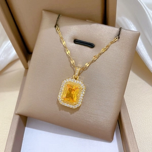 Détail du collier en or avec pendentif gemme jaune carrée dans un coffret cadeau chic