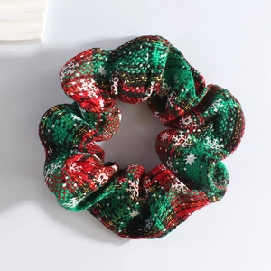Detailed view of red and green plaid plush scrunchie with white snowflake patterns