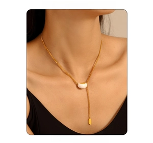 Close-up of gold-plated Y-necklace featuring a white bean pendant and Lucky tag detail