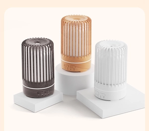 Three birdcage aroma diffusers in dark wood, light wood, and white on geometric stands