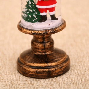 Macro detail of Christmas snow globe with Santa Claus and a vintage bronze base
