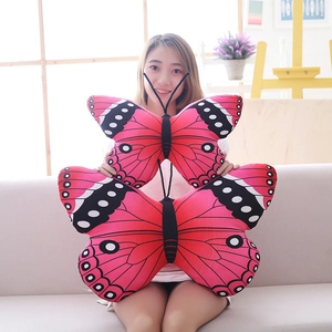 Pink butterfly shaped plush pillow in two sizes with realistic wing patterns on a sofa
