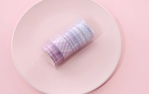 Detailed view of 5 rolls of purple plaid washi tape in a clear storage box