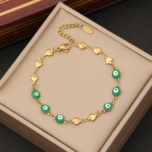 Detail of gold evil eye bracelet with heart links on a beige leather jewelry box