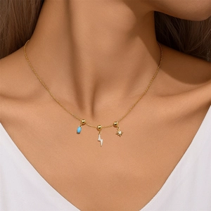 Close-up of a gold necklace with blue bead, diamond lightning and star charms on model