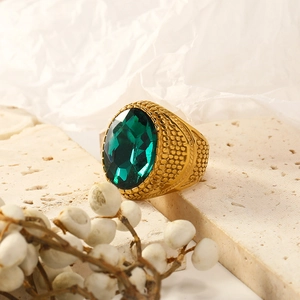 Close-up of vintage gold ring with large oval emerald gemstone and textured metal band