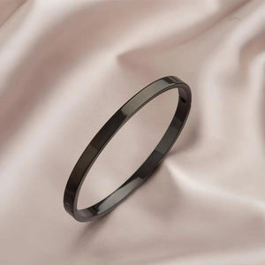 Polished black stainless steel minimalist bangle on elegant champagne silk background
