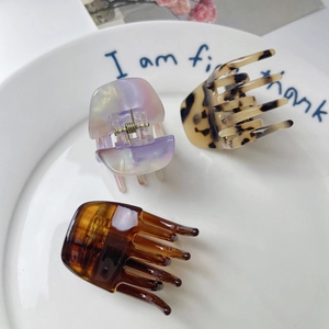 Detailed view of acetate hair claws in lavender, leopard, and amber patterns